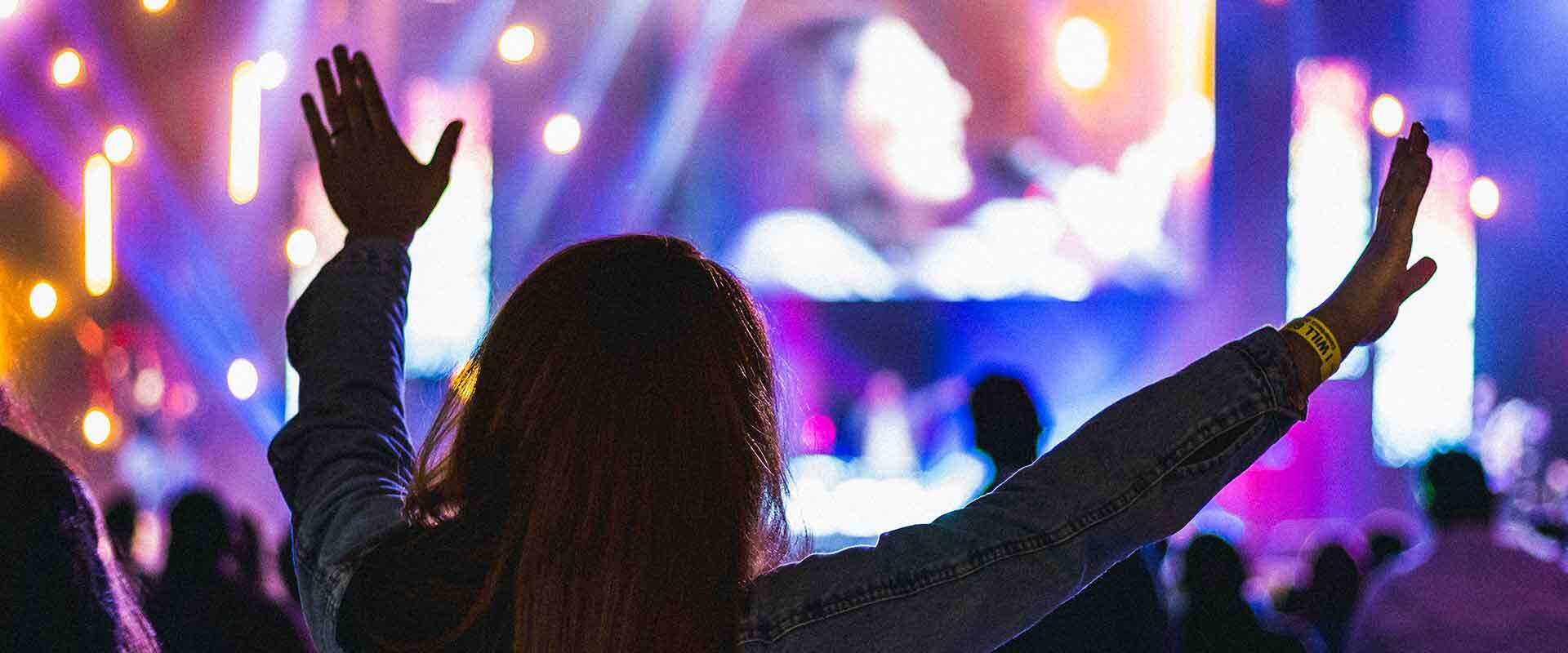 woman with arms raised at a worship concert