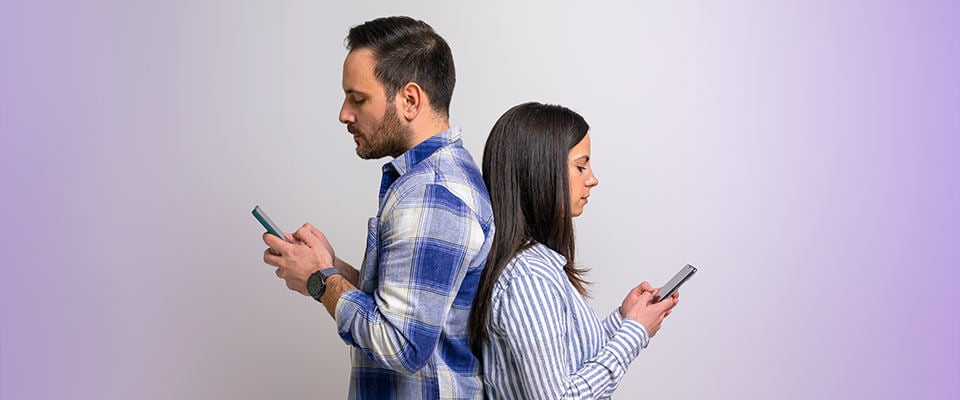 man and woman back to back looking at their mobile phones